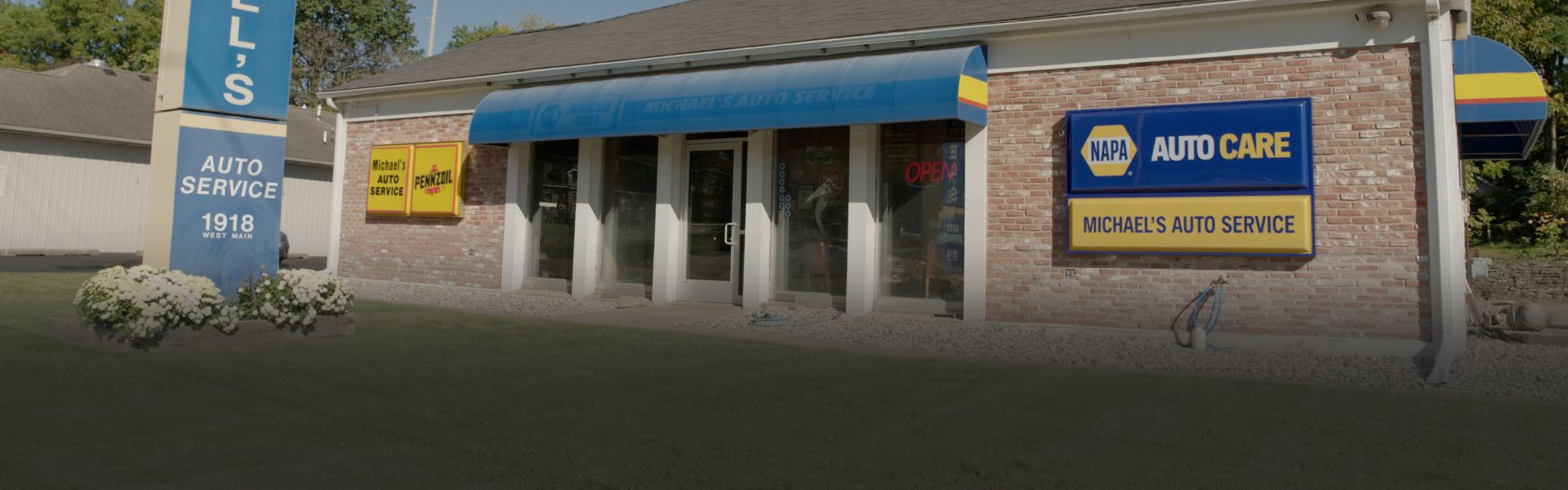 Small brick commercial building with blue awnings and a sign reading “MCDONALD’S” at night