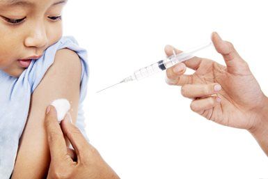 A medical professional prepares to administer an injection to a patient's upper arm, with a cotton swab applied to the skin.