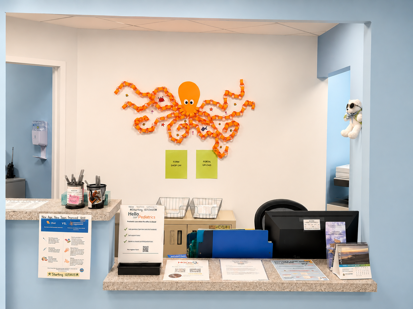 Front desk with orange octopus wall art, brochures, and a computer in a blue and white office lobby