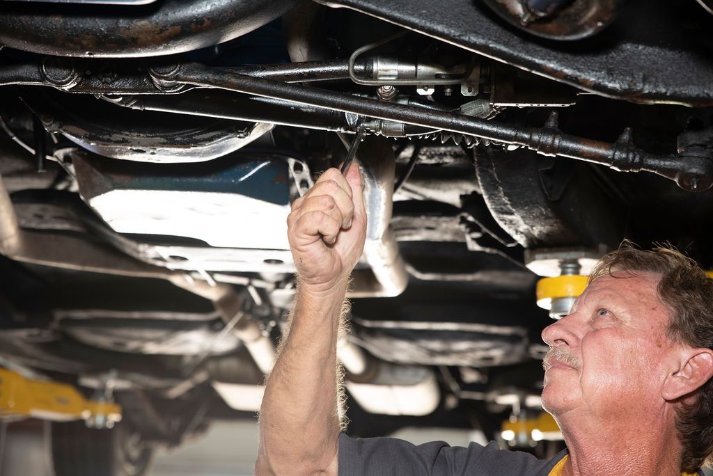 Mechanic inspecting the underside of a car on a lift with a flashlight