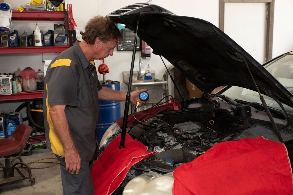 Mechanic inspecting a red car with its hood open in a garage