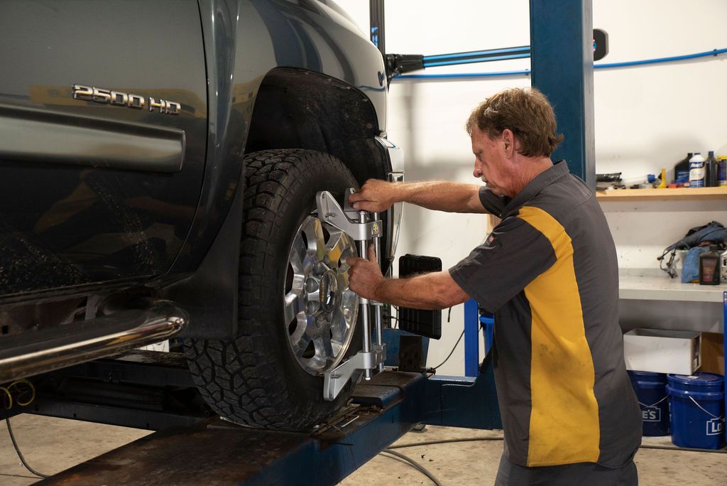 Mechanic tightening a wheel on a black SUV in a garage