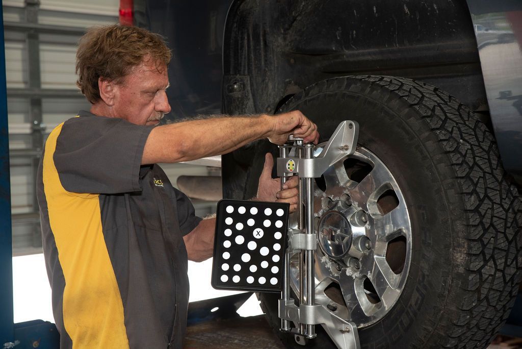 Mechanic aligning a wheel alignment machine on a truck tire in a garage