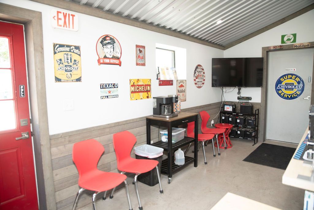 Small office break room with red chairs, black tables, wall signs, and a TV mounted on the wall