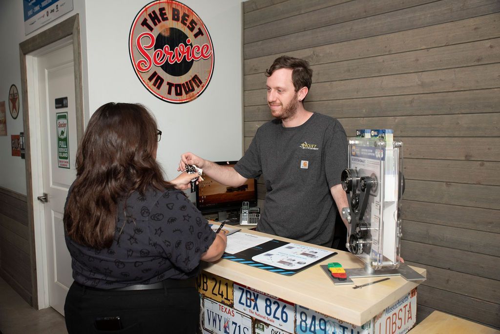 Man handing an item to a customer at a counter with license plates and a vending machine nearby