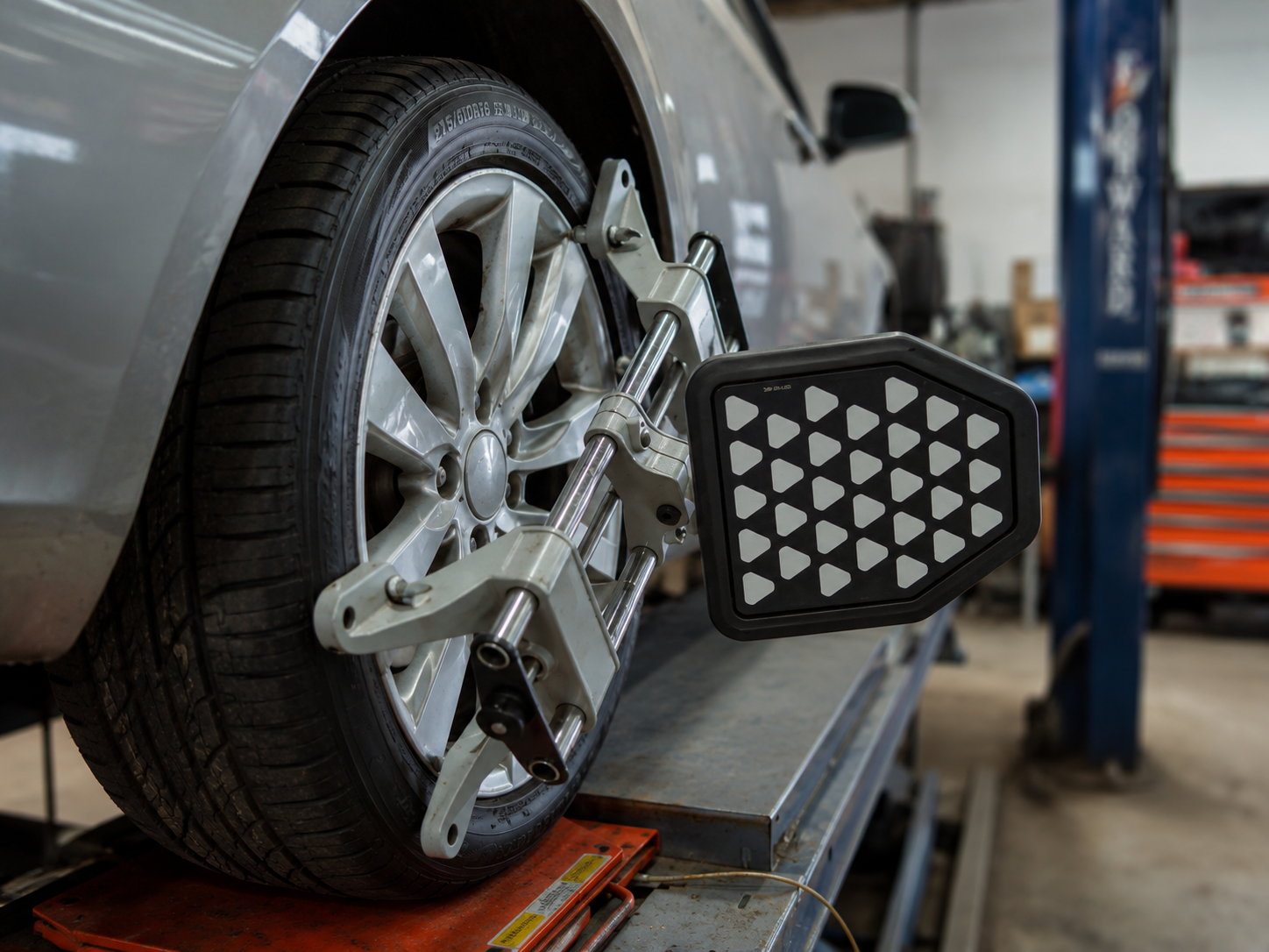 Car on a lift at a shop with a wheel alignment device attached to the front wheel