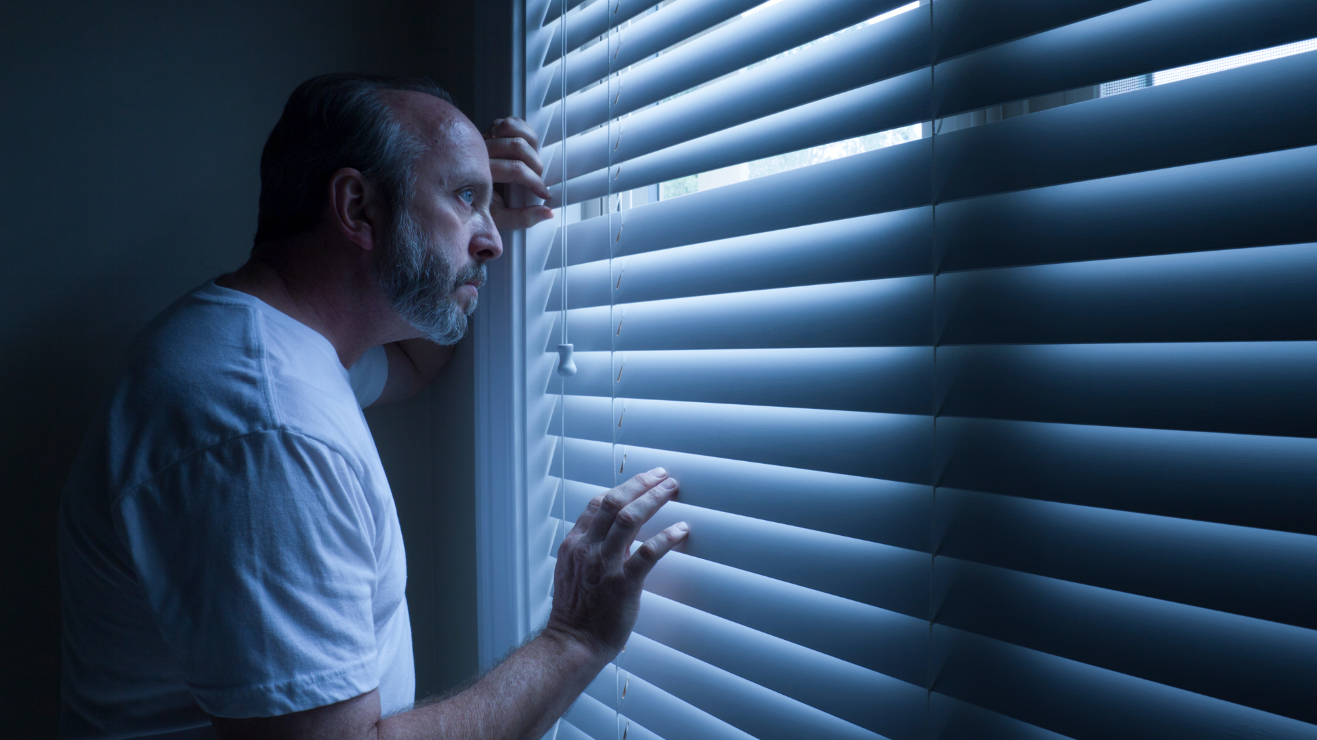 A man is looking out of a window at night.