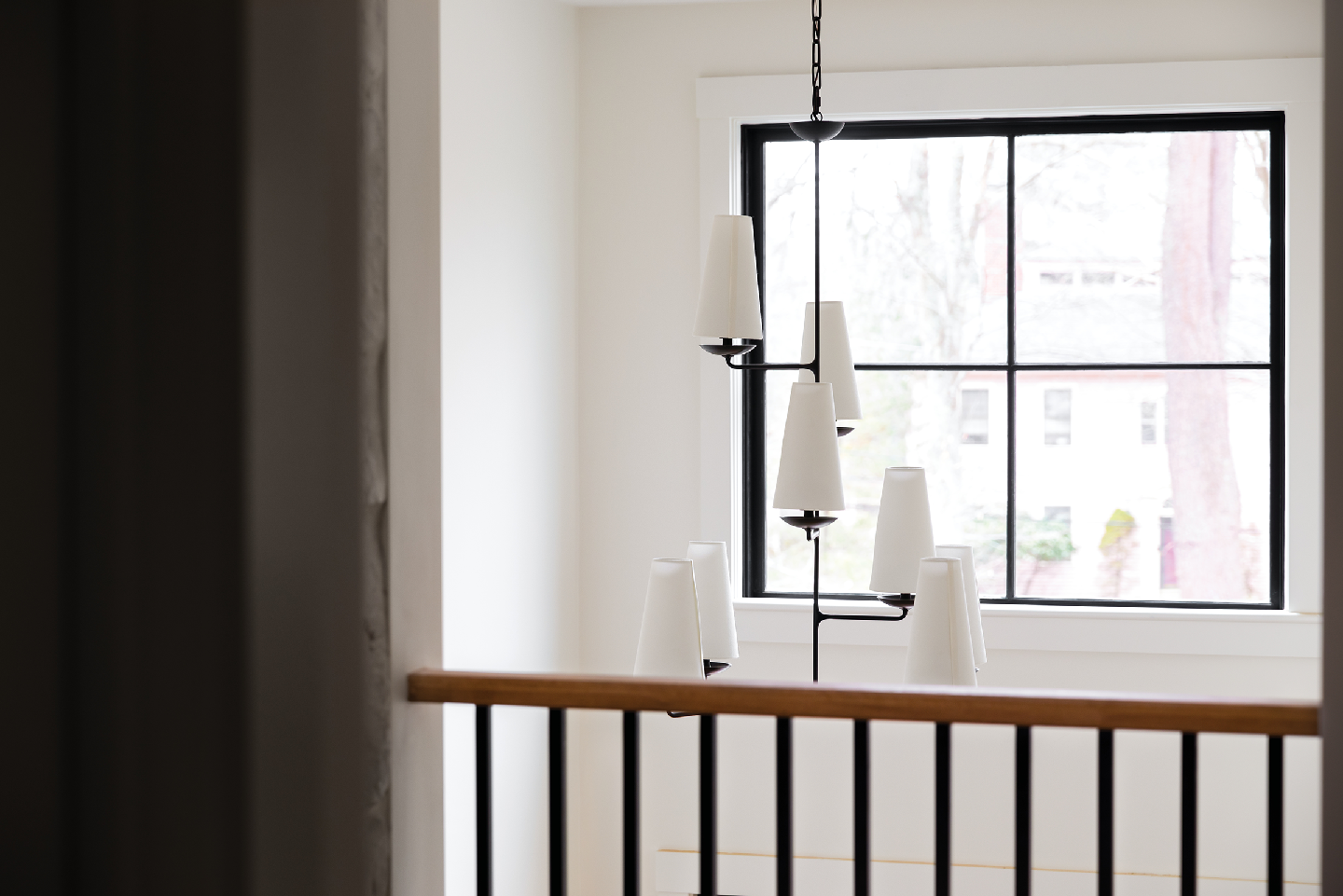 A staircase with a chandelier hanging from the ceiling and a window.
