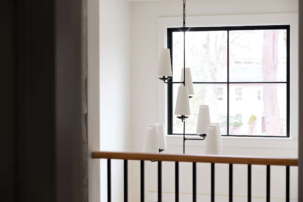 A staircase with a chandelier hanging from the ceiling and a window.