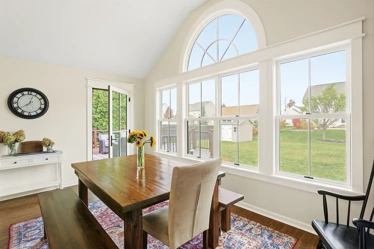 A dining room with a table and chairs and a clock on the wall.