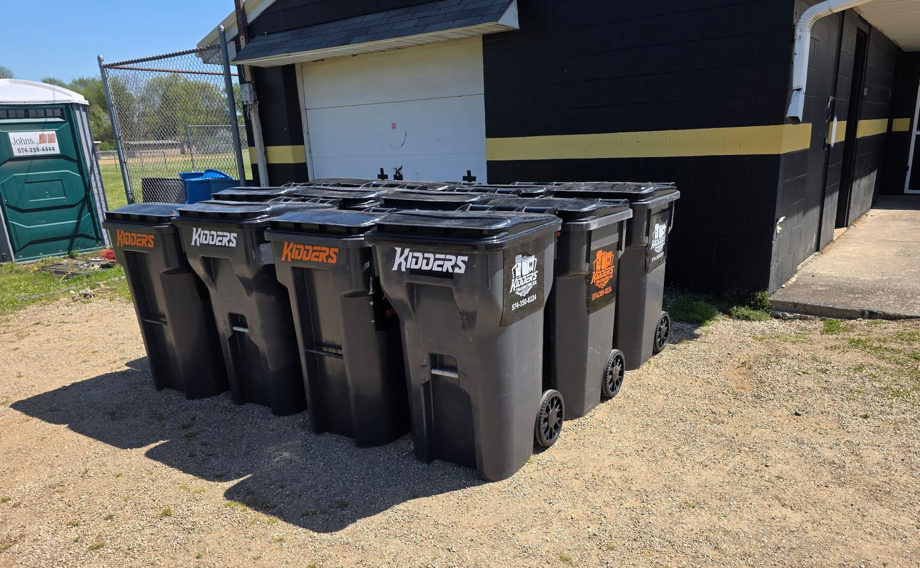 Orange Kidder's dumpster in front of a tan corrugated wall and garage door