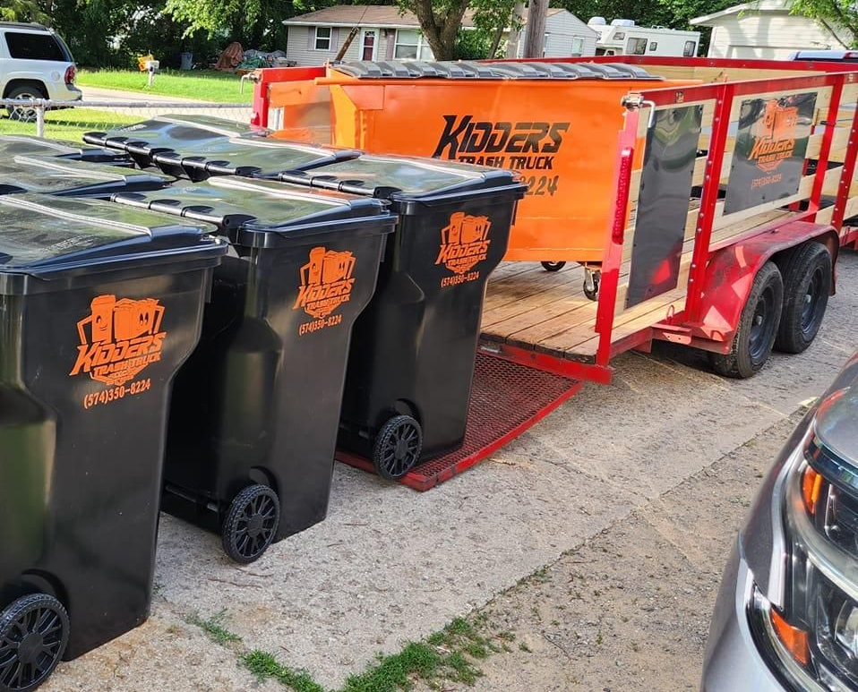 Orange Kidder's dumpster in front of a tan corrugated wall and garage door
