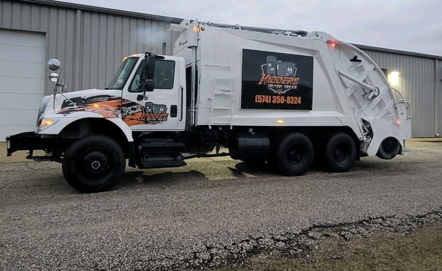 Orange Kidder's dumpster in front of a tan corrugated wall and garage door