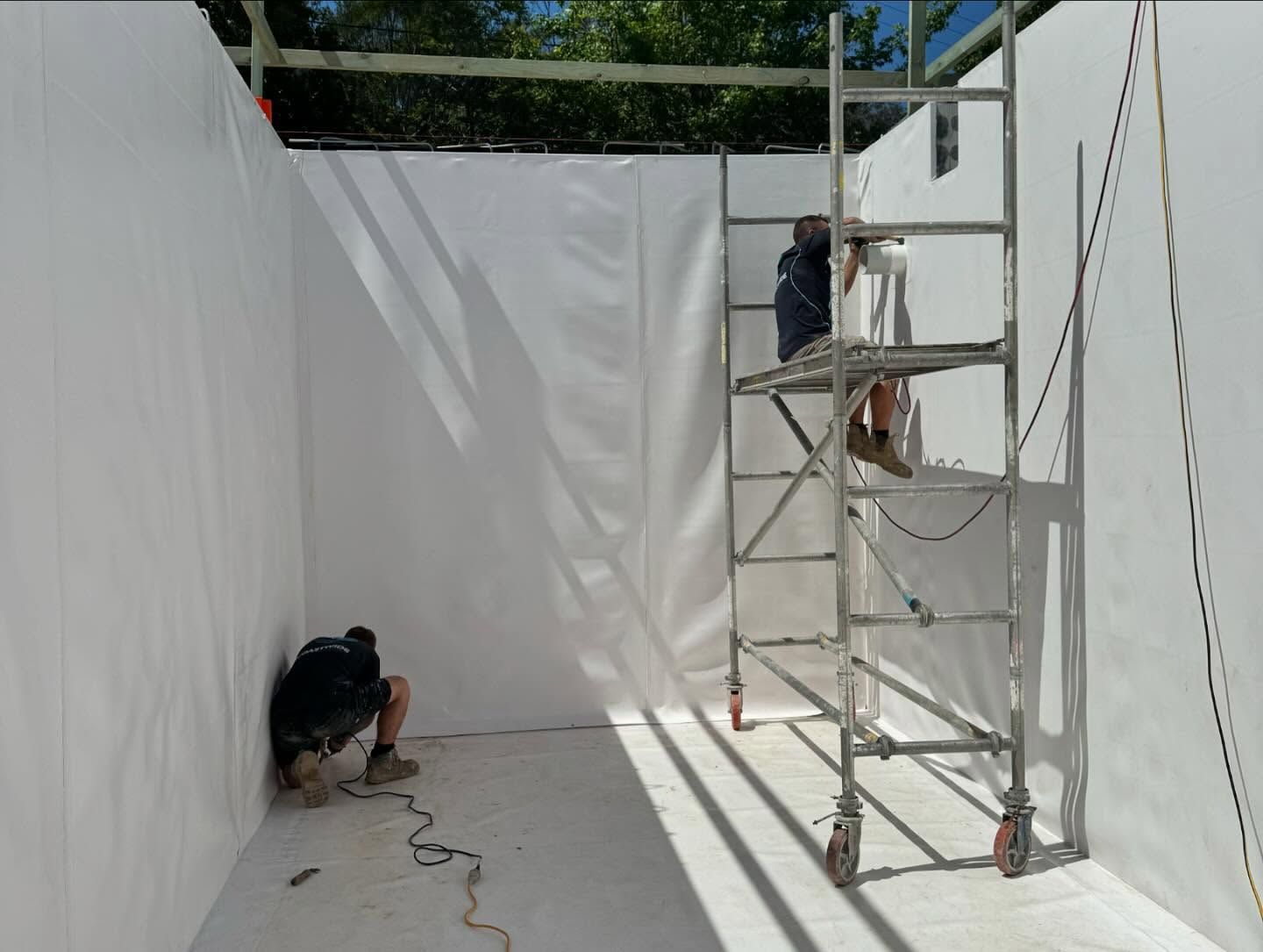 A Man Is Standing On A Scaffolding In Front Of A White Wall — Coastwide Waterproofing in Terrigal, NSW