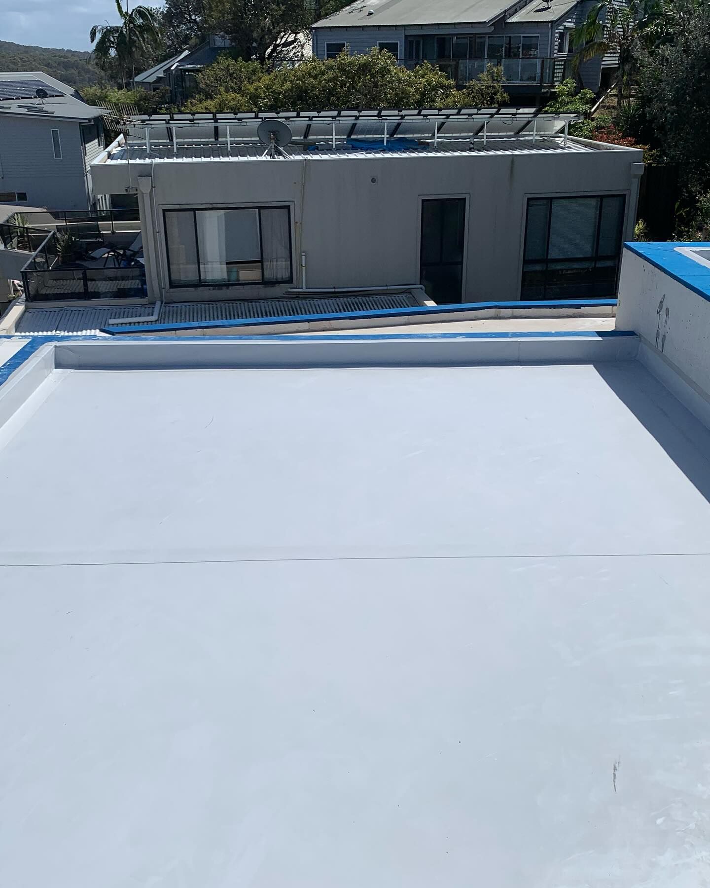 A White Roof With A Blue Trim Is Sitting On Top Of A Building — Coastwide Waterproofing in West Gosford, NSW