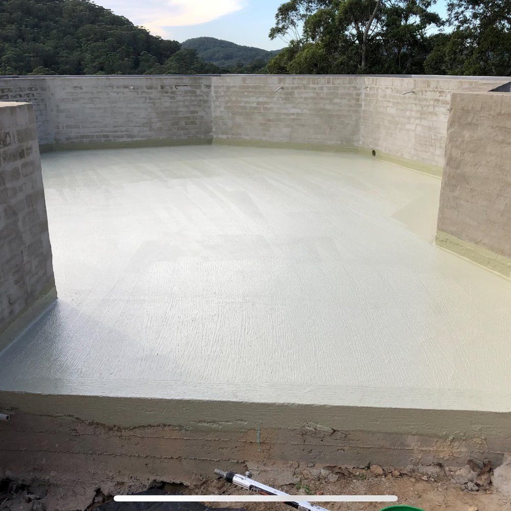 A White Concrete Floor With A Brick Wall In The Background — Coastwide Waterproofing in West Gosford, NSW