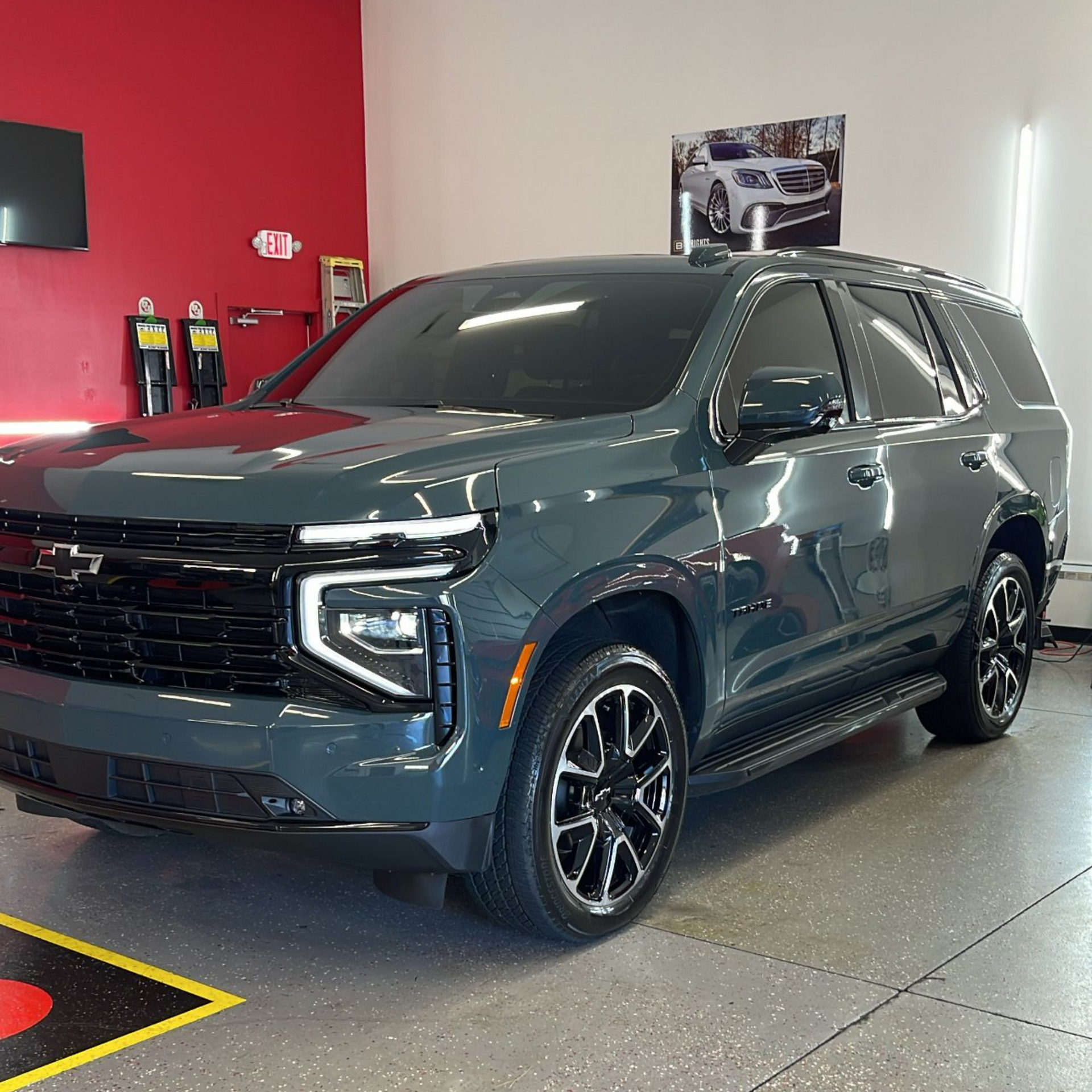 Dark teal Chevrolet Tahoe SUV in a showroom with black accents.