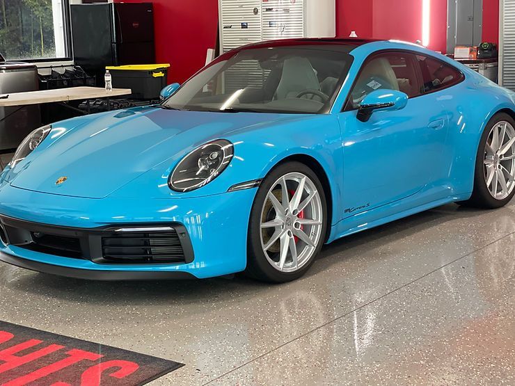 Bright blue Porsche sports car in a showroom with red accents.