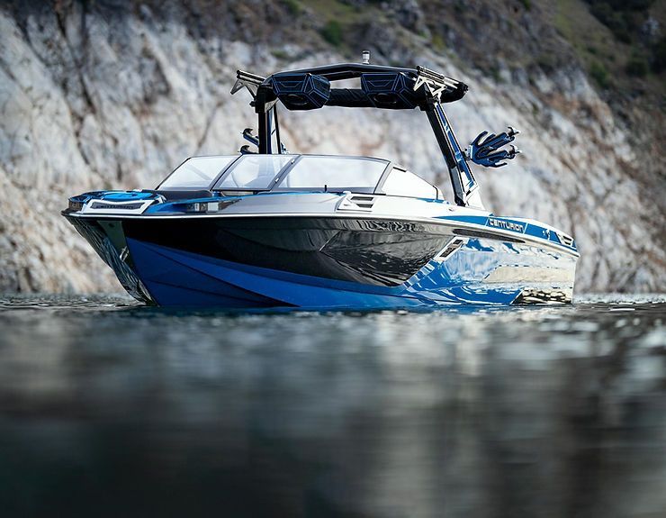 Blue and black motorboat on water, with rocky background.