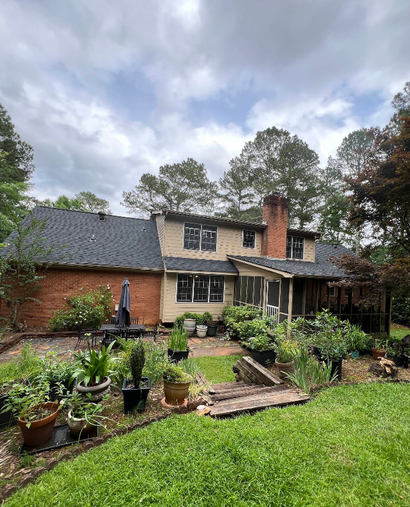 Backyard garden with potted succulents in front of a brick house under cloudy skies