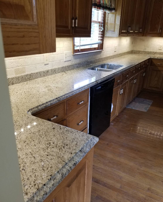 Modern kitchen with speckled granite countertops, wood cabinets, and a window above the sink.