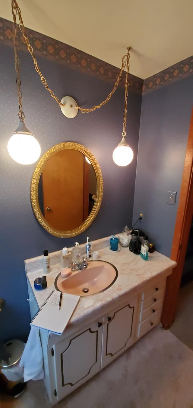 A bathroom with a sink , mirror and lamps.