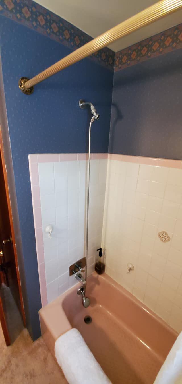 A bathroom with a pink bathtub and a shower.
