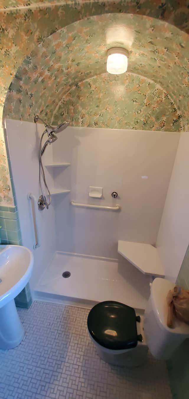 A bathroom with a toilet , sink and shower.