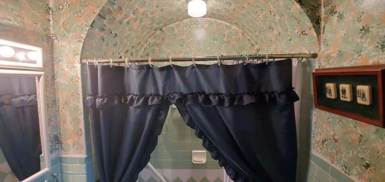 A bathroom with a shower curtain and a mirror.