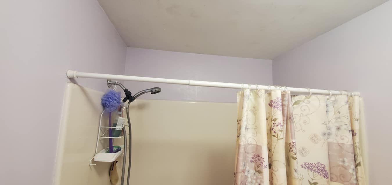 A bathroom with a shower curtain and a shower head.
