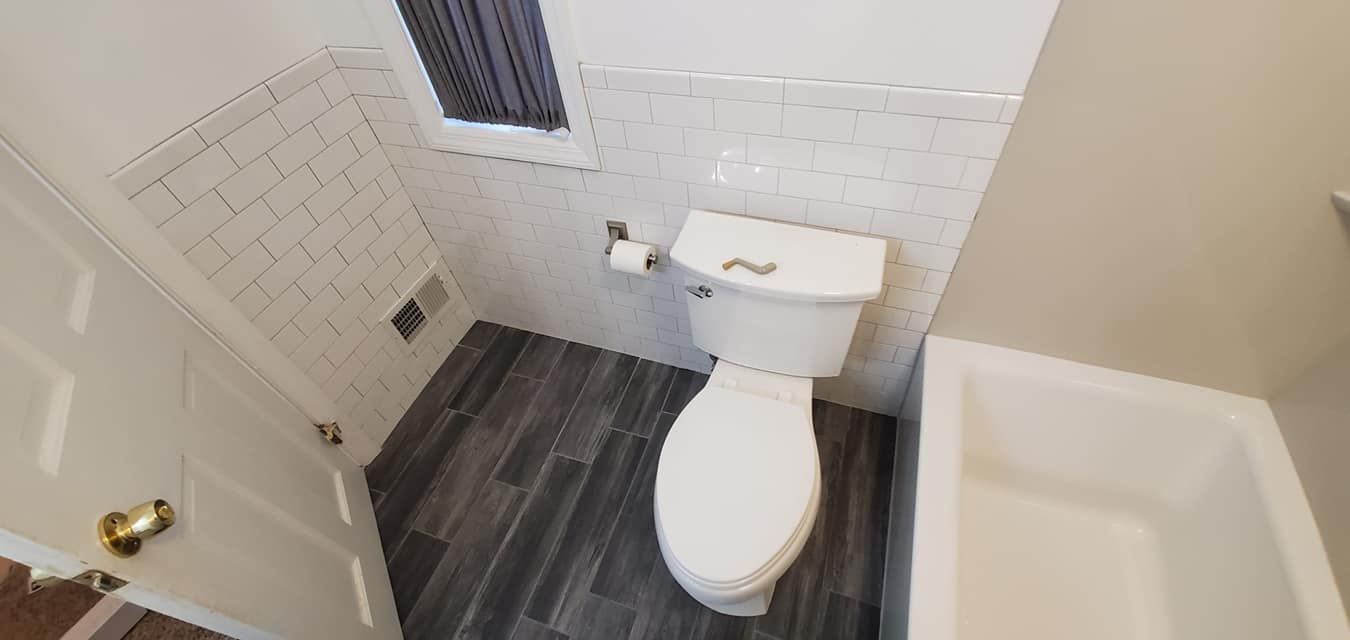 A bathroom with a toilet , tub and shower.