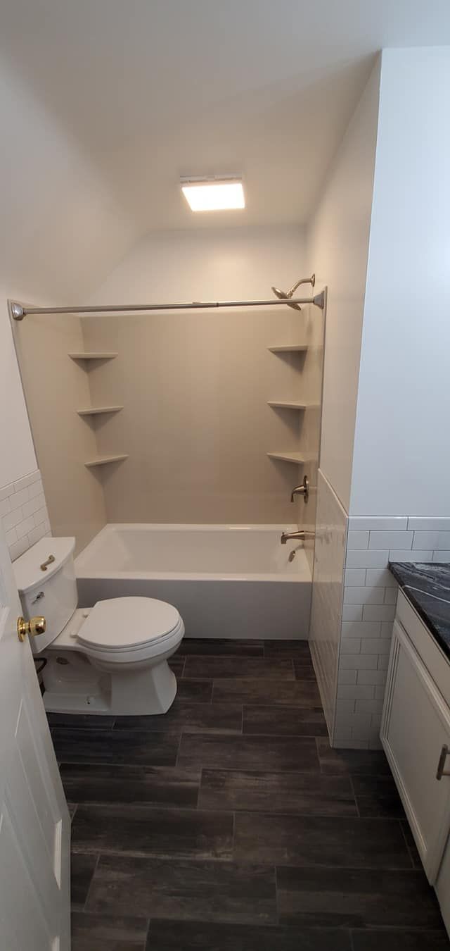 A bathroom with a toilet , bathtub and shower.