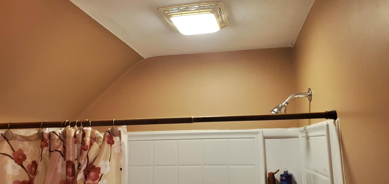 A bathroom with a shower curtain and a light on the ceiling.