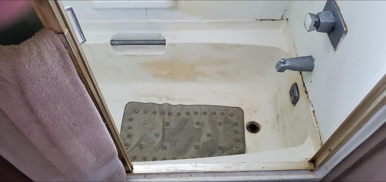 A bathtub in a bathroom with a rug on the floor.
