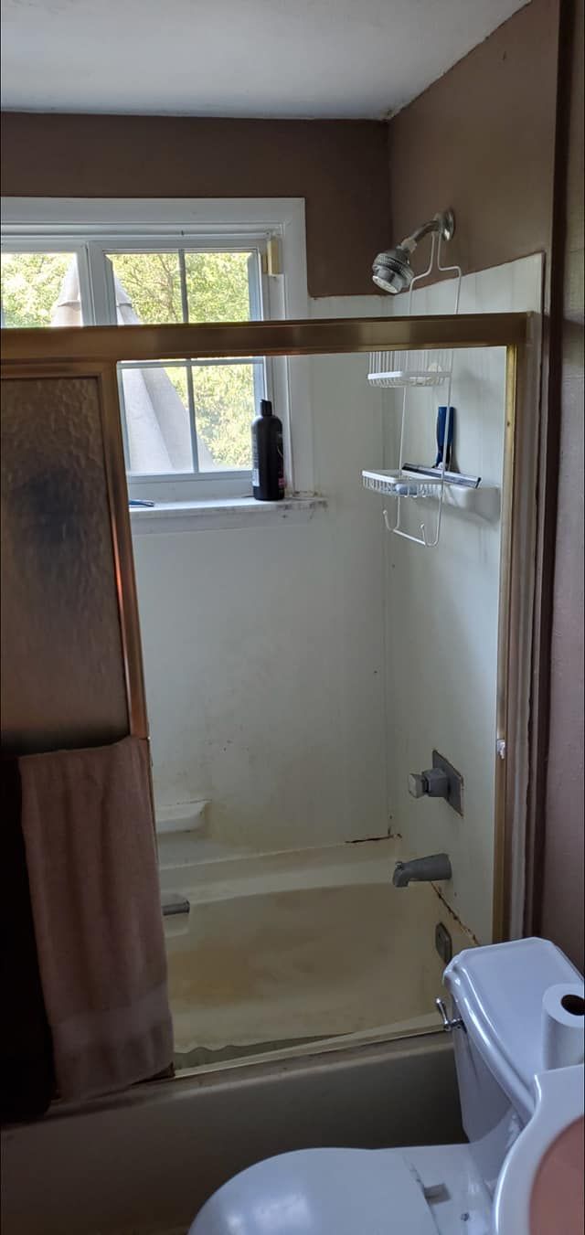 A bathroom with a tub , toilet , sink and shower.