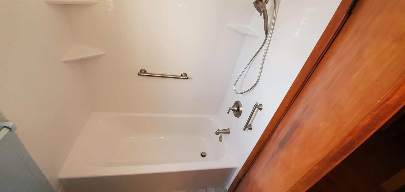 A bathroom with a bathtub and a shower head.
