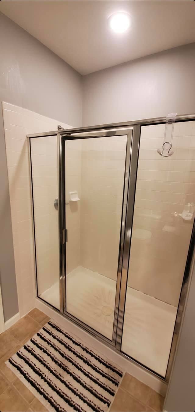 A bathroom with a walk in shower and a striped rug.