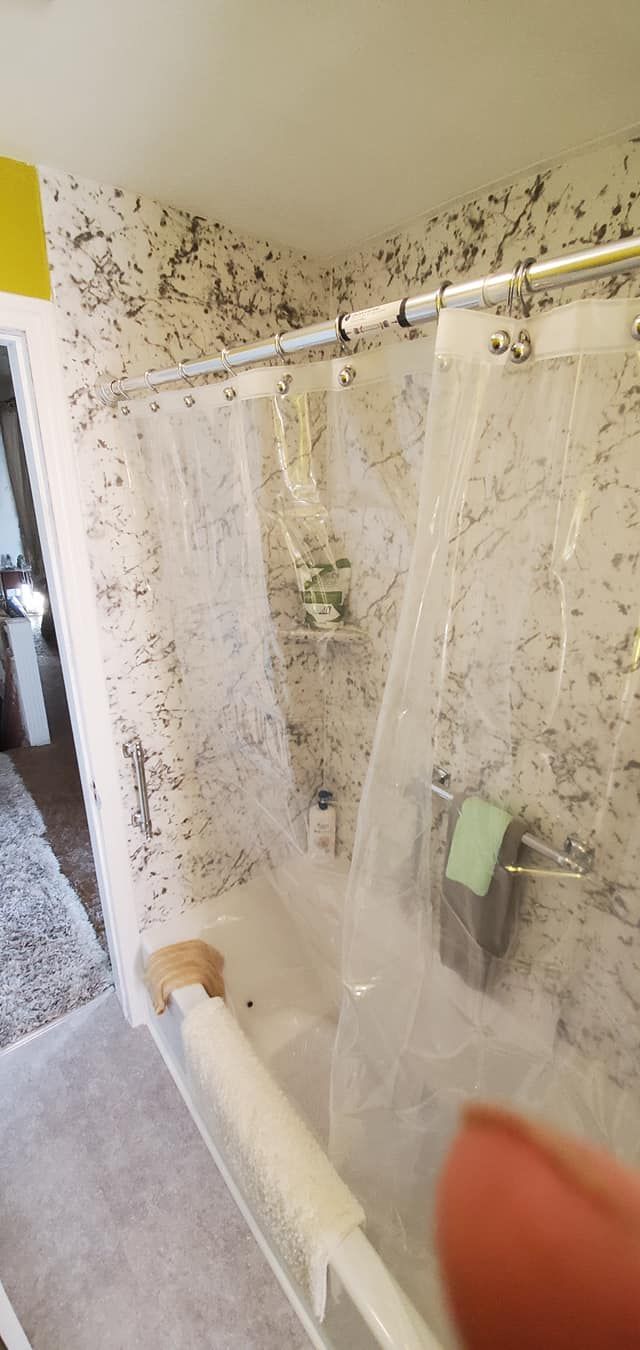 A person is holding a shower curtain in a bathroom.