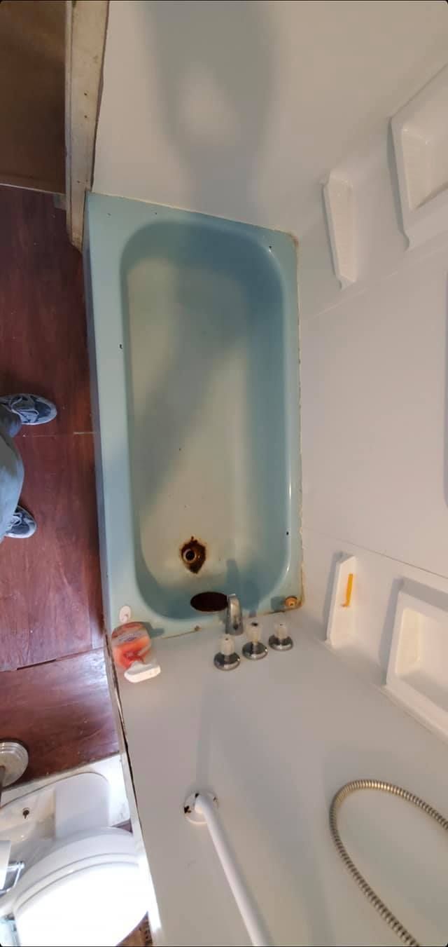 A bathroom with a blue bathtub and a toilet.