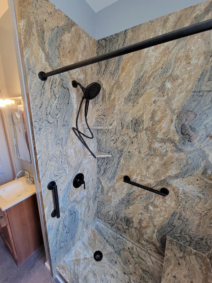 A bathroom with a shower , sink , and handrails.