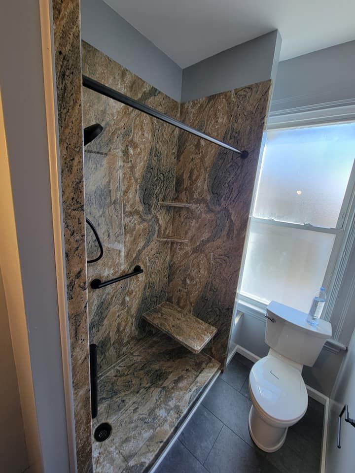 A bathroom with a toilet , shower , and window.