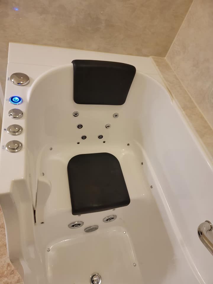 A white bathtub with a black seat in it.