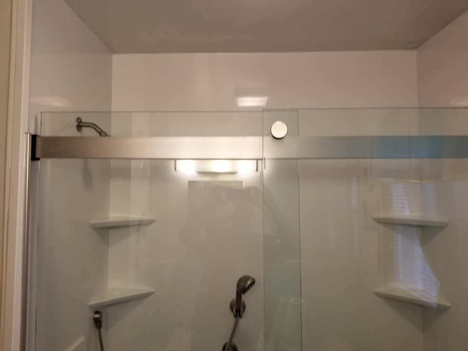 A bathroom with a sliding glass shower door and shelves.