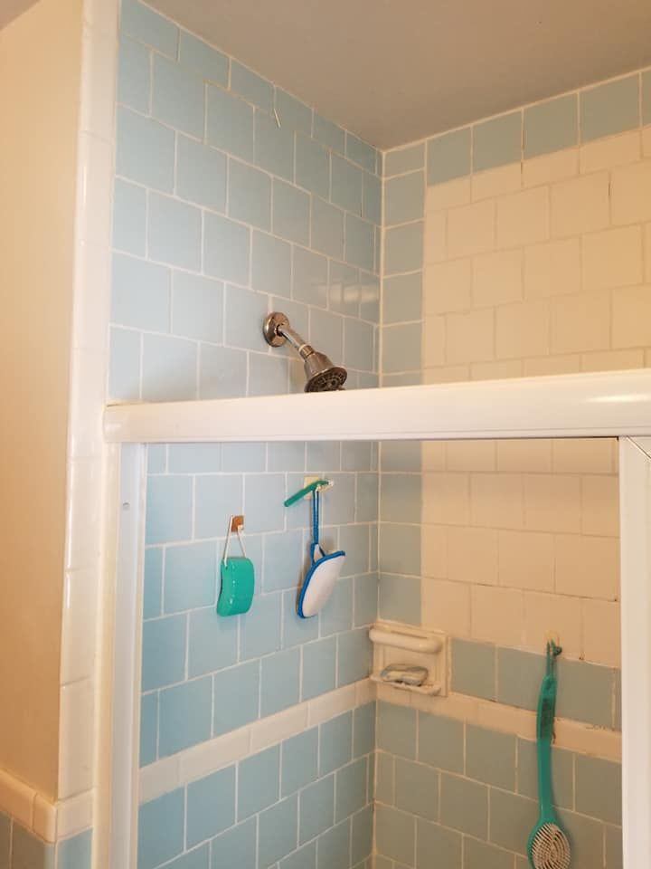 A bathroom with blue tiles and a shower head.