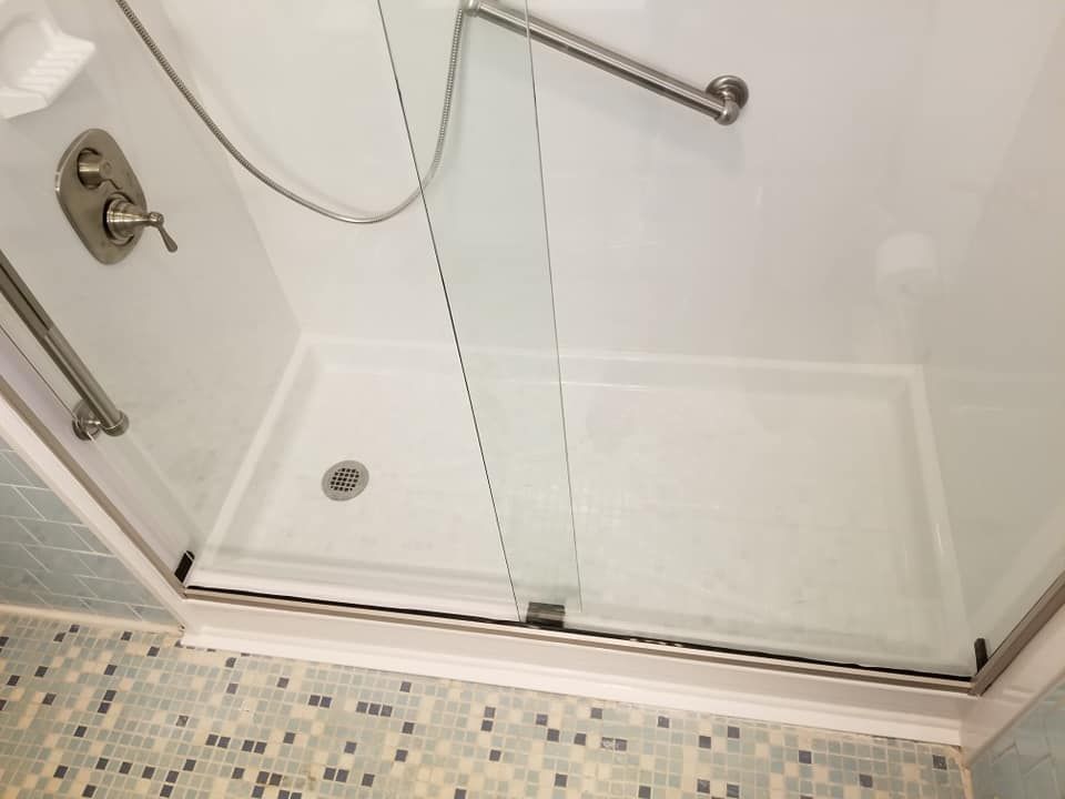 A bathroom with a walk in shower with a glass door
