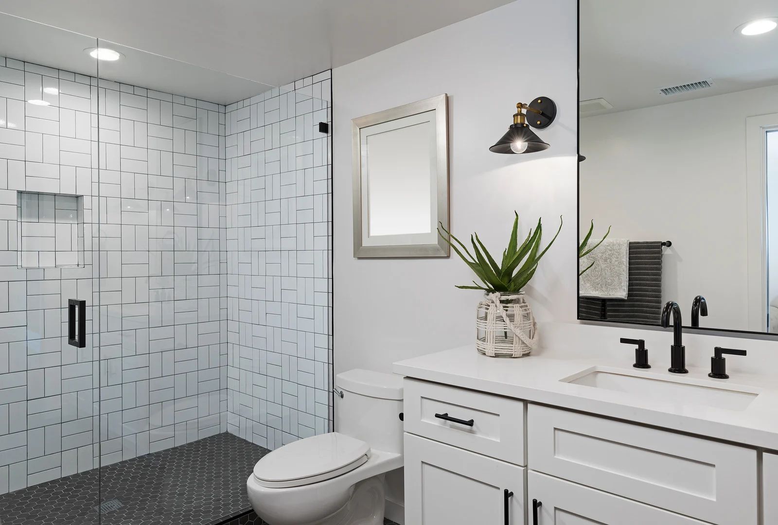Modern bathroom with glass shower, white vanity, mirror, and toilet