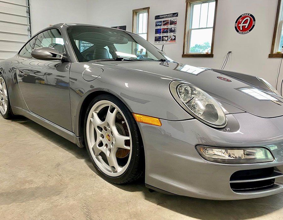 Silver sports car parked indoors in a garage, front-left view.