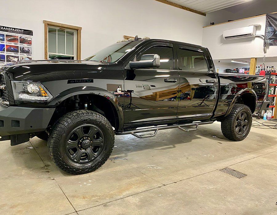Black lifted pickup truck in a garage, shown from the side on a concrete floor