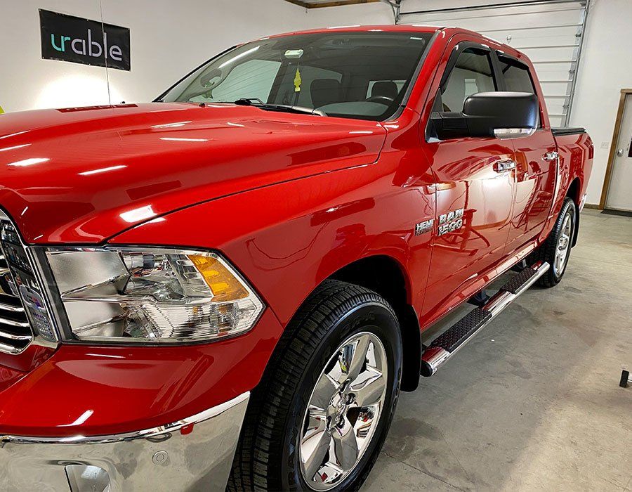 Red pickup truck in a showroom, angled front-left view, with glossy paint and chrome wheels