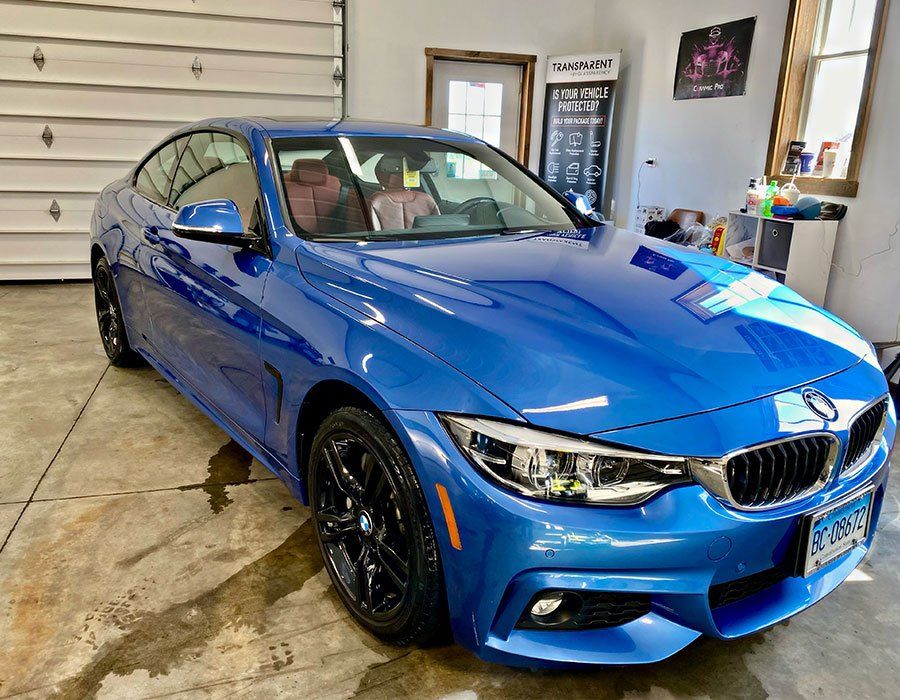 Blue BMW coupe parked in a garage, angled front view with black wheels.